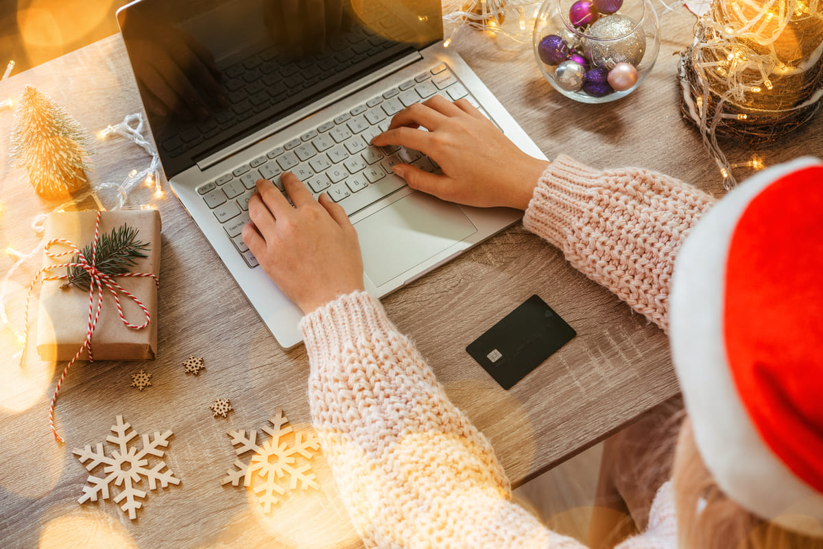 девушка в новогодней шапке сидит за ноутбуком